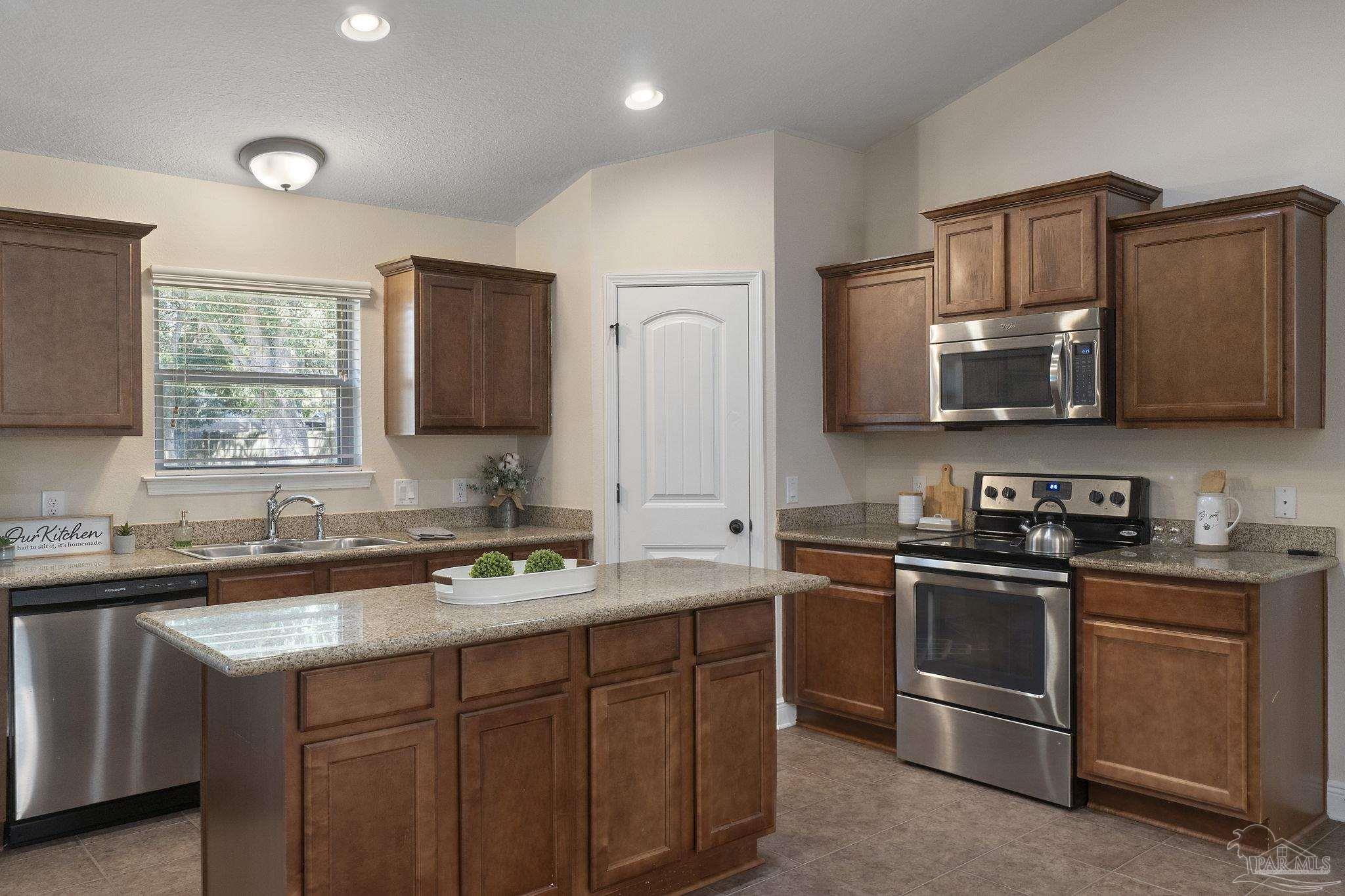 5607 Cane Syrup Circle Pace, FL 32571 - Photo 20 of 54 a kitchen with stainless steel appliances granite countertop a sink stove and microwave