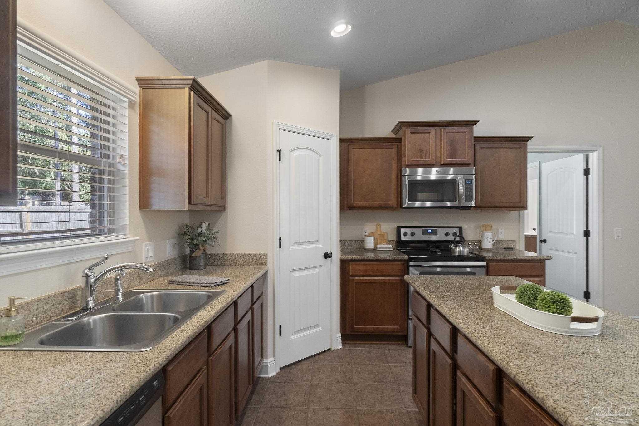 5607 Cane Syrup Circle Pace, FL 32571 - Photo 21 of 54 a kitchen with stainless steel appliances granite countertop a sink a stove and a wooden cabinets
