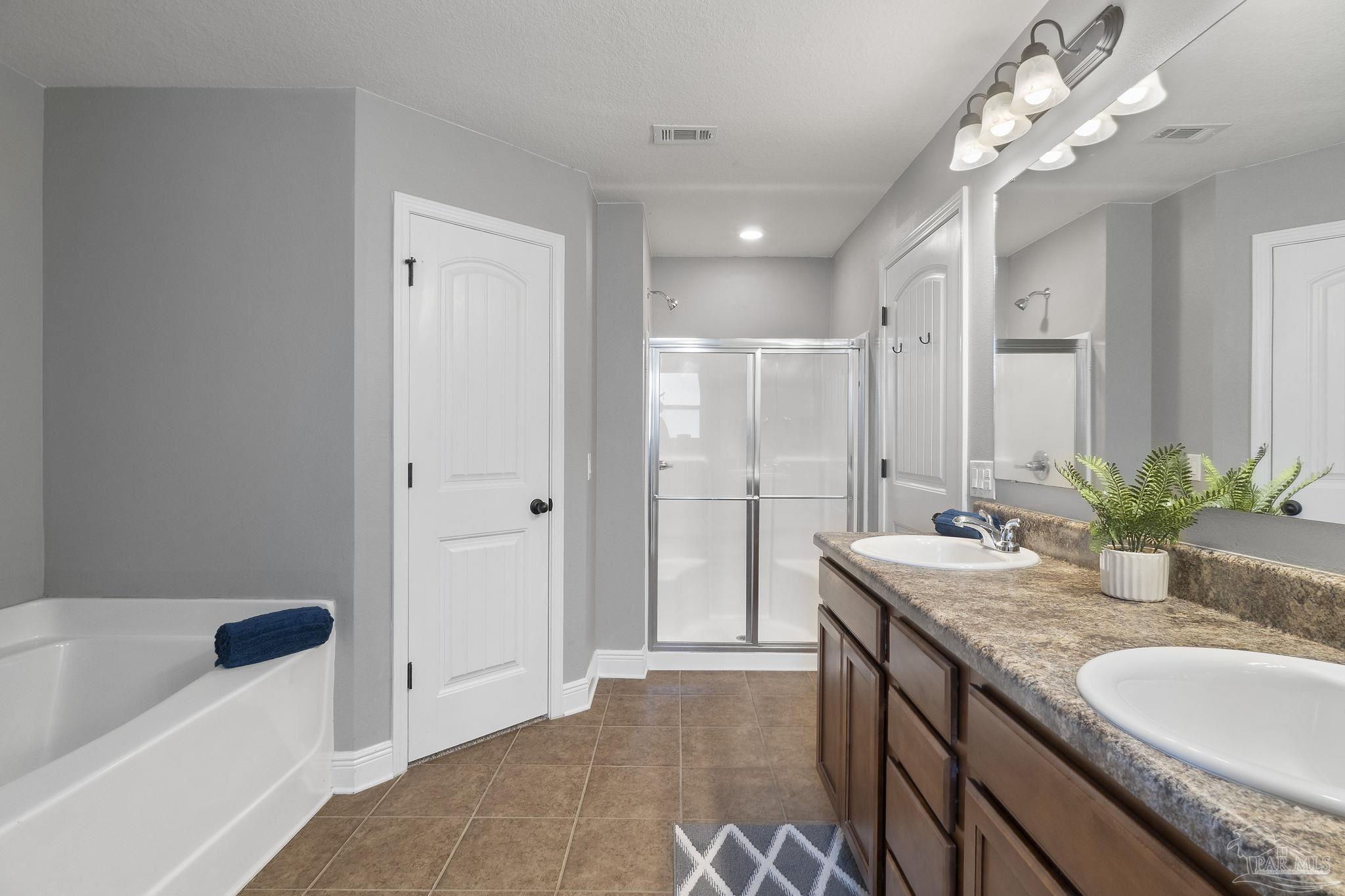 5607 Cane Syrup Circle Pace, FL 32571 - Photo 30 of 54 a bathroom with a granite countertop sink a large mirror and a bathtub
