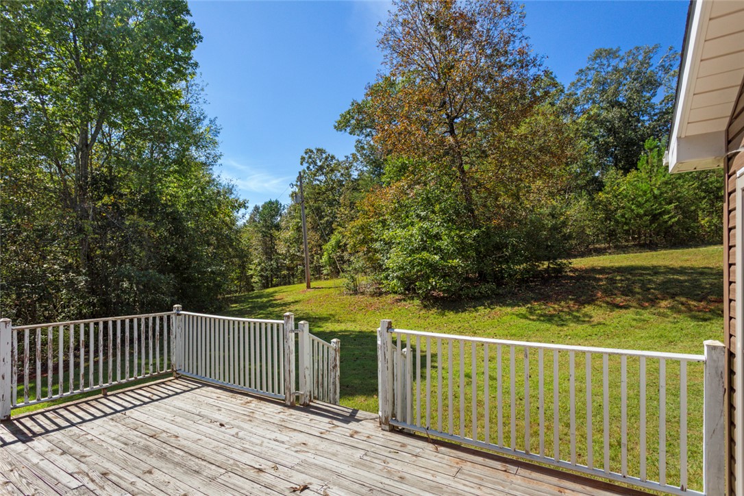 621 Burns Mill Road West Union, SC 29696 - Photo 29 of 45 A spacious wooden deck extends to a verdant yard, offering peaceful views of mature trees and open skies.