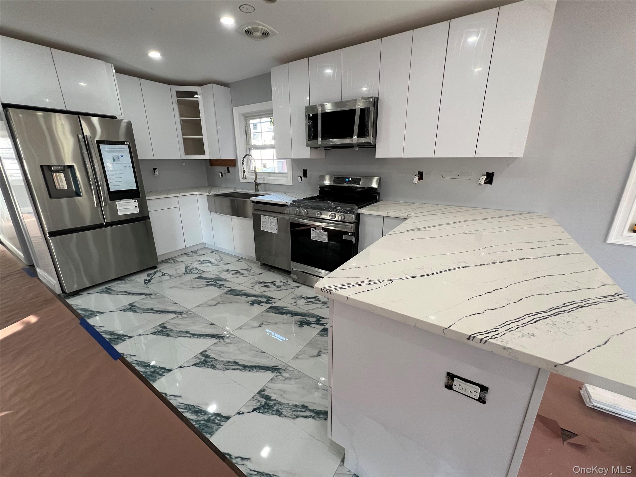 98-29 Albert Road Queens, NY 11417 - Photo 11 of 13 Kitchen with light marble finish floors, stainless steel appliances, light stone counters, white cabinets, and modern cabinets