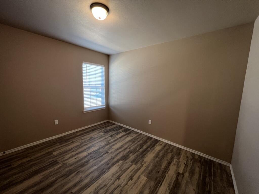 7413 5th Street, Unit 2 Lubbock, TX 79416 - Photo 8 of 19 a view of an empty room with wooden floor and a window
