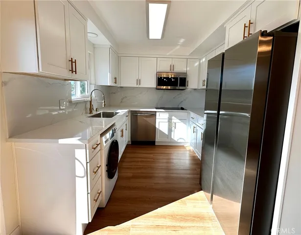 a kitchen with stainless steel appliances granite countertop a refrigerator a stove and a sink