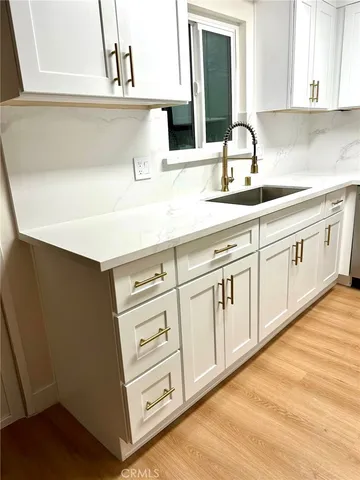 a kitchen with white cabinets and sink