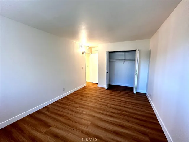 a view of an empty room with wooden floor and window