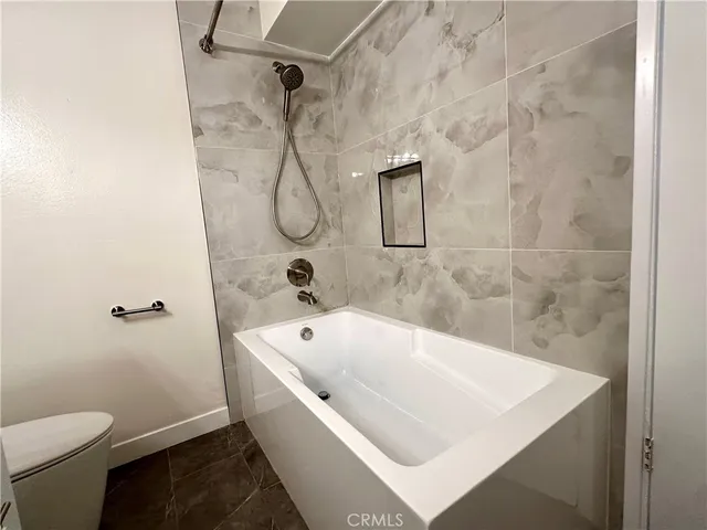 a bath tub sitting next to a white toilet and a shower