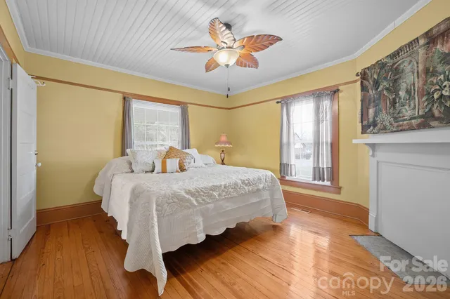a bedroom with a bed and dresser with wooden floor