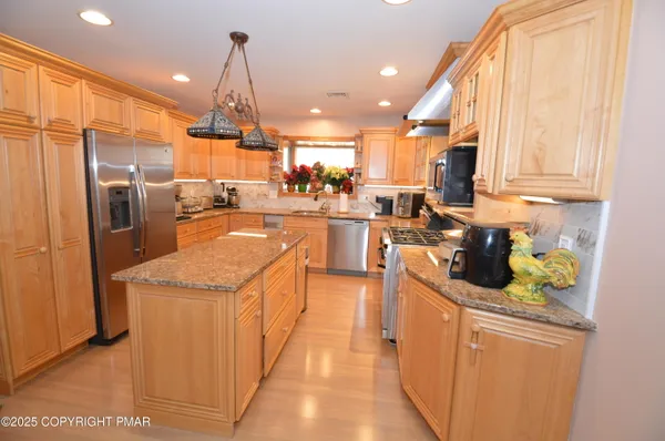 a kitchen with stainless steel appliances granite countertop a sink stove and refrigerator