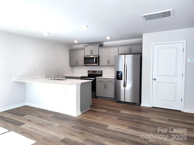 a kitchen with granite countertop a refrigerator and a stove top oven