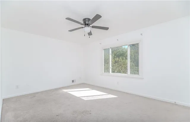 an empty room with a window and a fan