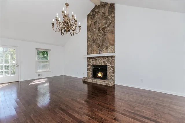 an empty room with wooden floor a fireplace and windows