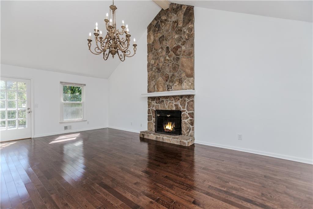 3408 Hamilton Mill Road Buford, GA 30519 - Photo 3 of 32 an empty room with wooden floor a fireplace and windows