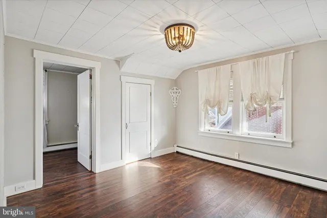 an empty room with wooden floor chandelier and windows