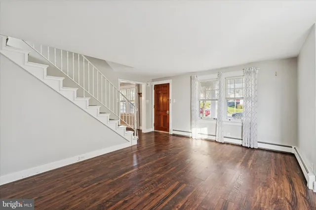 a view of an empty room with wooden floor and stairs