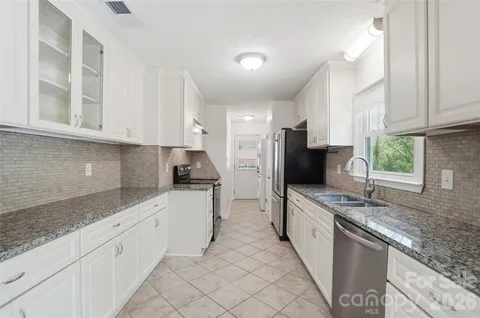 a kitchen with granite countertop white cabinets and stainless steel appliances