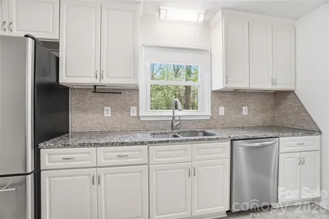 a kitchen with granite countertop white cabinets and a sink
