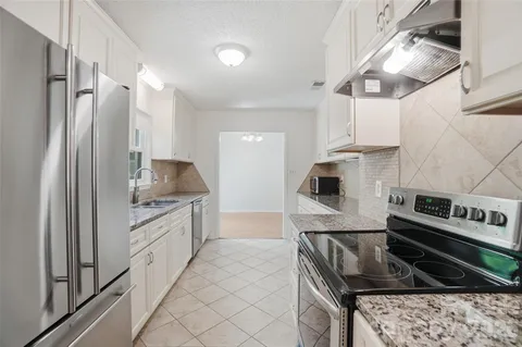 a kitchen with stainless steel appliances kitchen island granite countertop a stove refrigerator and microwave