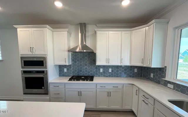 a kitchen with stainless steel appliances white cabinets and a window
