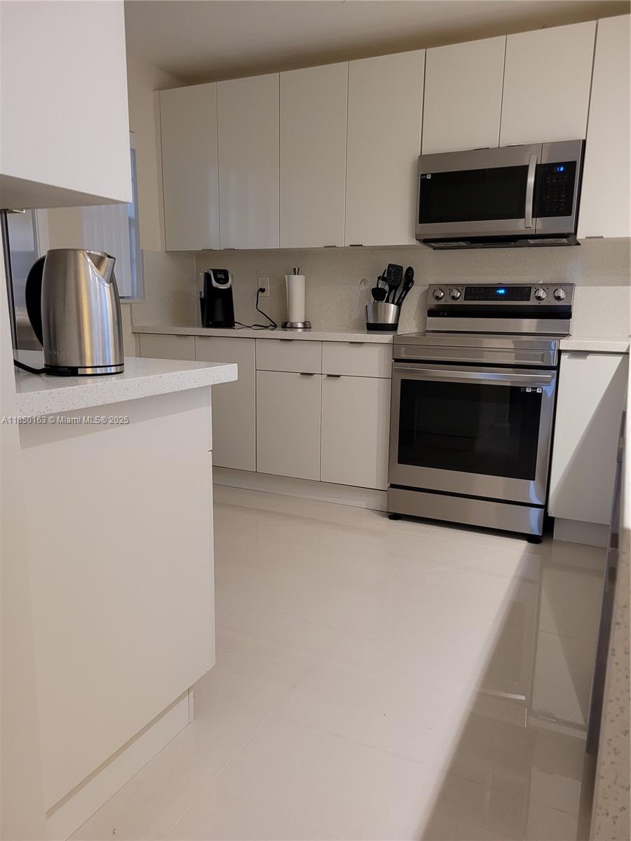 8101 Southwest 24th Court, Unit 108 Davie, FL 33324 - Photo 3 of 10 a kitchen with cabinets a microwave a sink and a stove