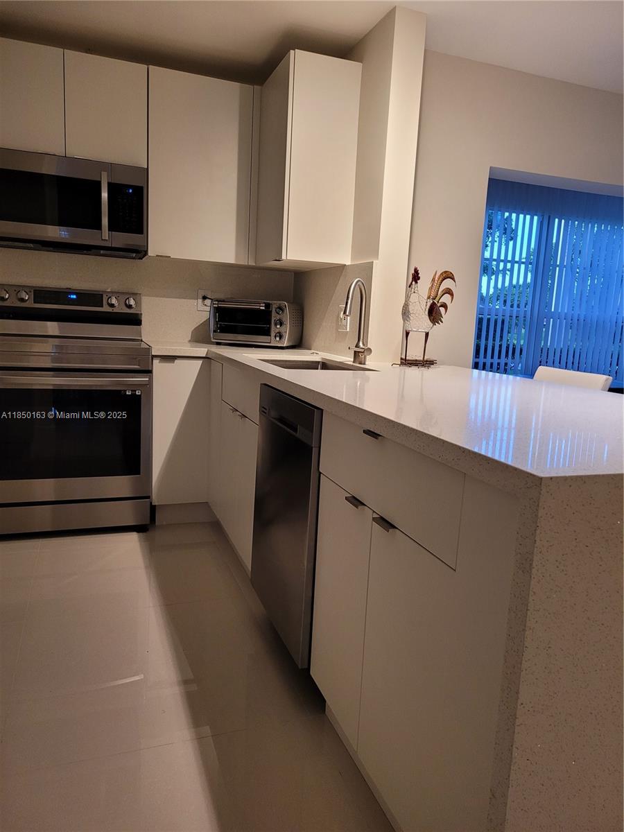 8101 Southwest 24th Court, Unit 108 Davie, FL 33324 - Photo 4 of 10 a kitchen with a sink and a stove top oven