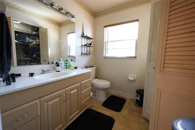 a bathroom with a double vanity sink toilet mirror and window