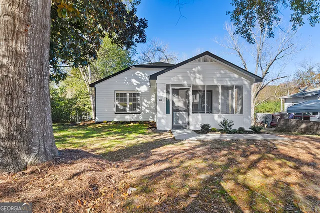 a view of a house with a yard and large tree