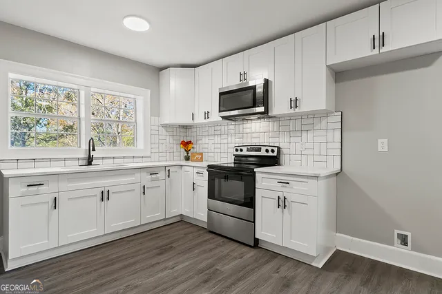 a kitchen with cabinets stainless steel appliances a sink and a window
