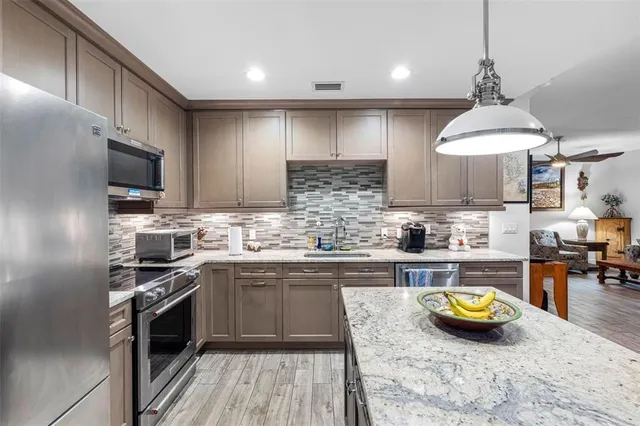 a kitchen with kitchen island granite countertop wooden cabinets and stainless steel appliances