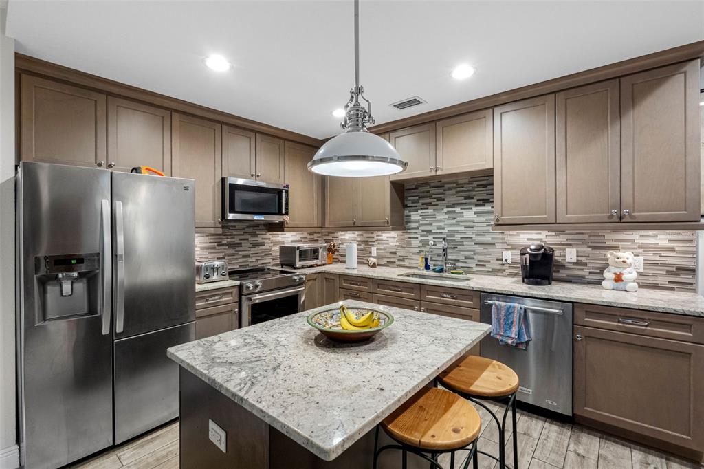 763 Date Palm Lane St. Petersburg, FL 33707 - Photo 5 of 34 a kitchen with stainless steel appliances granite countertop a sink a stove a refrigerator cabinets a center island and chairs