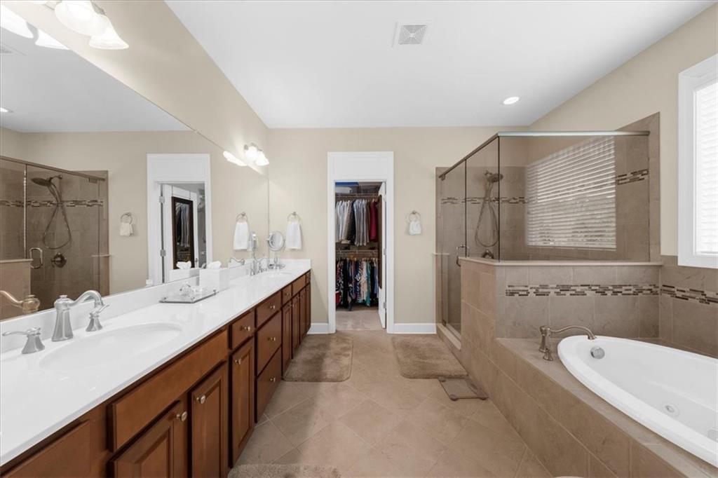 3709 Maple Shade Drive Southwest Gainesville, GA 30504 - Photo 32 of 81 a bathroom with a granite countertop double vanity sink a large mirror a bathtub and shower