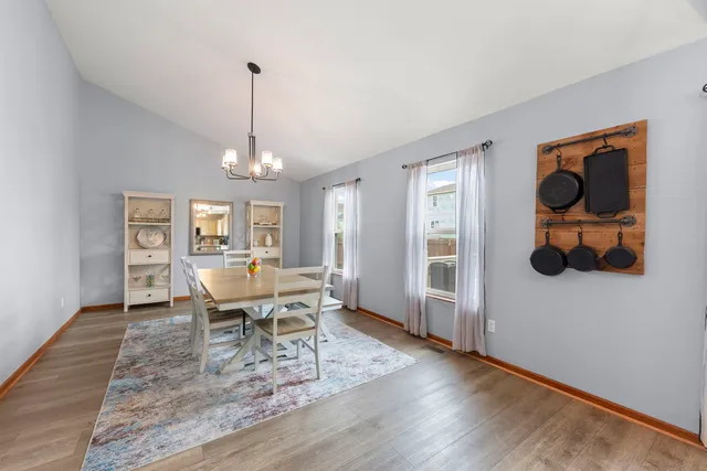 a dining room with wooden floor a chandelier a glass table and chairs