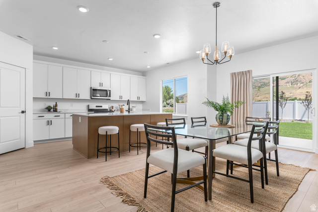1352 West 2350 South, Unit 18 Perry, UT 84302 - Photo 6 of 26 Open-concept kitchen and dining area featuring light wood-finish flooring, white cabinetry, and stainless steel appliances