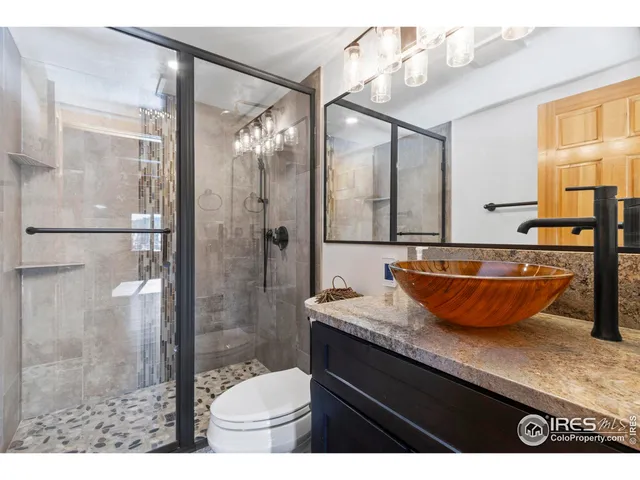 a bathroom with a granite countertop sink a toilet a mirror and shower