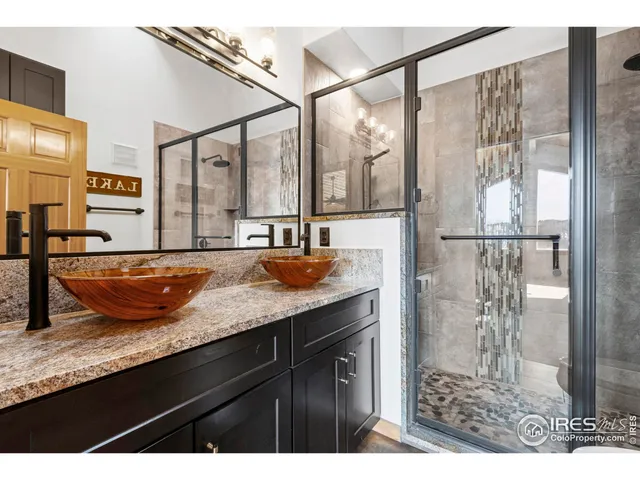 a bathroom with a granite countertop sink a mirror and shower