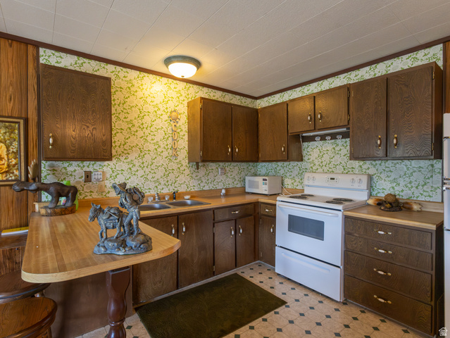4770 Pine Crest Road Evanston, UT 82930 - Photo 23 of 24 Kitchen featuring wood-finish cabinetry, a double basin sink, and a built-in breakfast bar