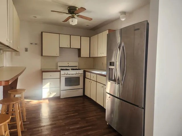 a kitchen with stainless steel appliances granite countertop a refrigerator a stove a sink dishwasher and white cabinets with wooden floor