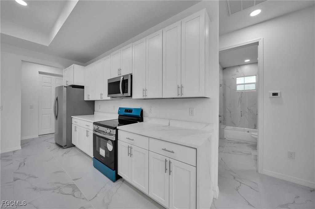 4308 15th Street Southwest Lehigh Acres, FL 33976 - Photo 6 of 27 a kitchen with white cabinets and stainless steel appliances