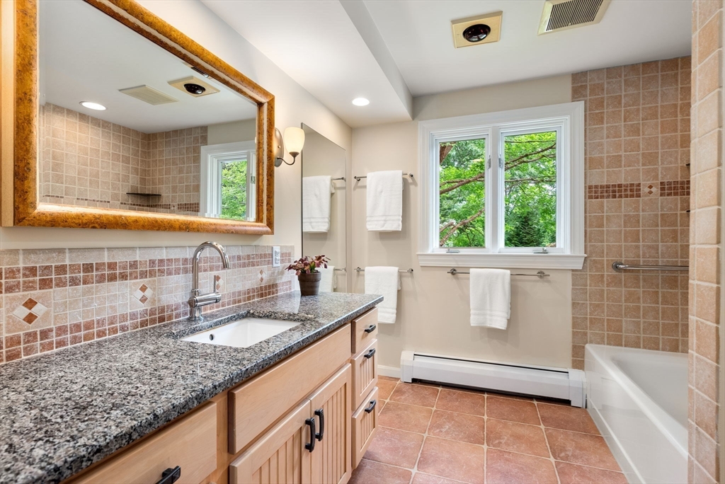 120 Lincoln Road Wayland, MA 01778 - Photo 26 of 34 a bathroom with a granite countertop sink a mirror a bathtub and next to a window