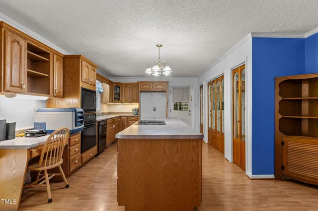 a large kitchen with granite countertop a stove a sink a dining table and chairs