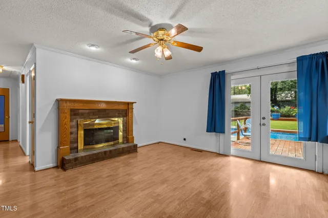 an empty room with windows fireplace and a ceiling fan