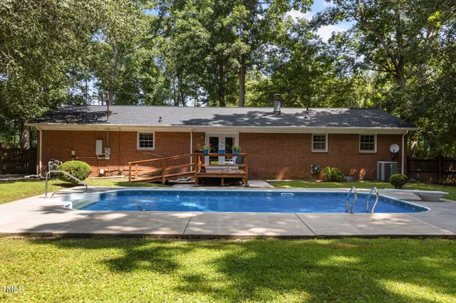 a view of house with garden and swimming pool