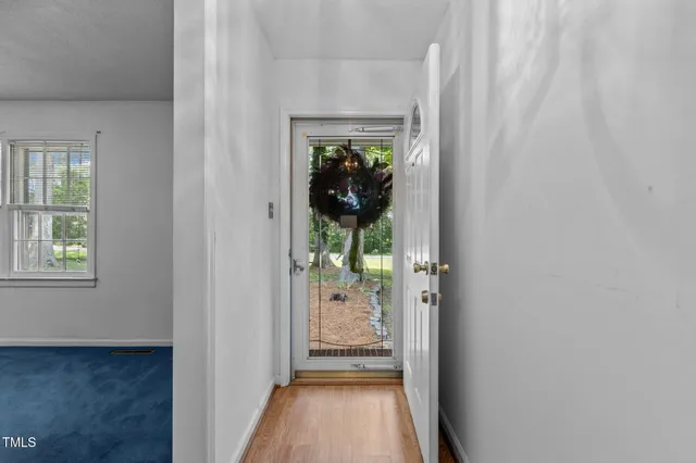 a view of a hallway with wooden floor and a dining room