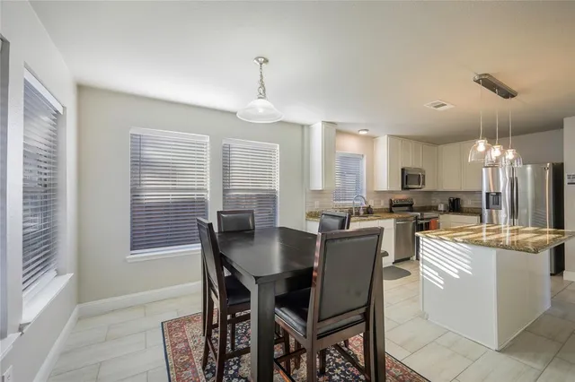 a dining room with kitchen island stainless steel appliances furniture a chandelier and a view of kitchen