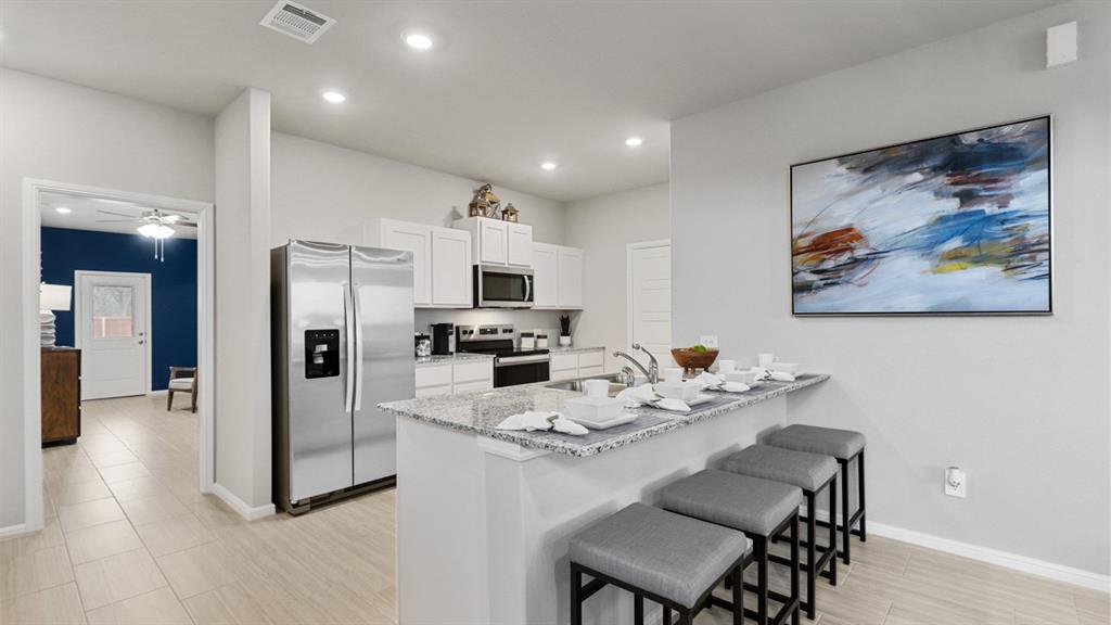 a kitchen with stainless steel appliances granite countertop a refrigerator a stove a microwave oven a dining table and chairs with wooden floor