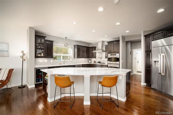 a kitchen with stainless steel appliances granite countertop a refrigerator a stove a sink dishwasher a dining table and chairs with wooden floor