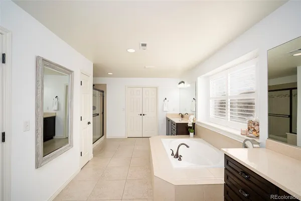 a spacious bathroom with a tub sink shower and mirror