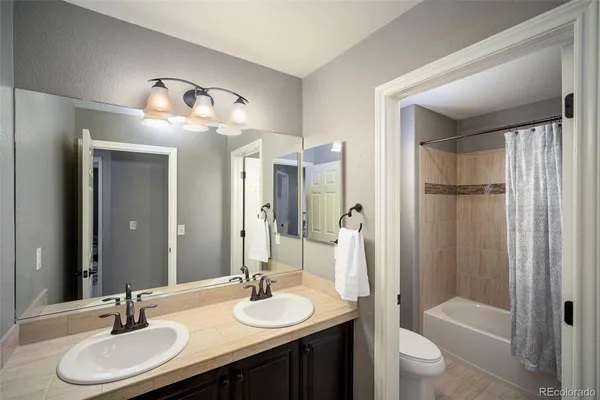 a bathroom with a double vanity sink toilet mirror and shower