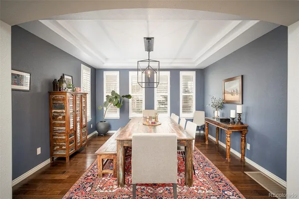 a dining room with wooden floor and large windows