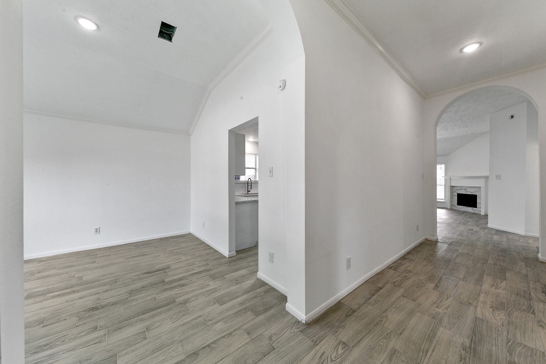 12014 Raven View Drive Houston, TX 77067 - Photo 7 of 29 Bright, open interior with arched doorways and wood-style flooring. The layout includes a view into the kitchen and a cozy living area with a fireplace. Ideal for modern living.