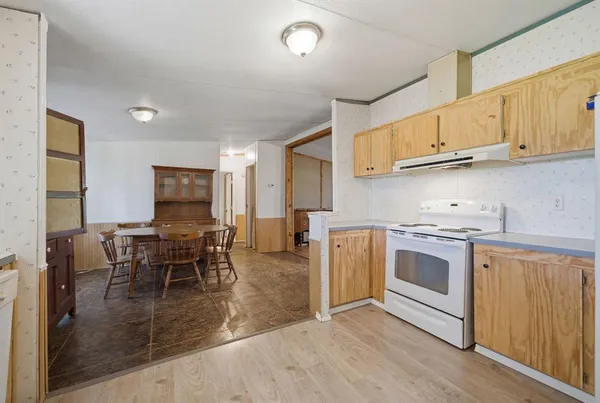 a kitchen with stainless steel appliances granite countertop a stove top oven a sink dishwasher a dining table and chairs with wooden floor